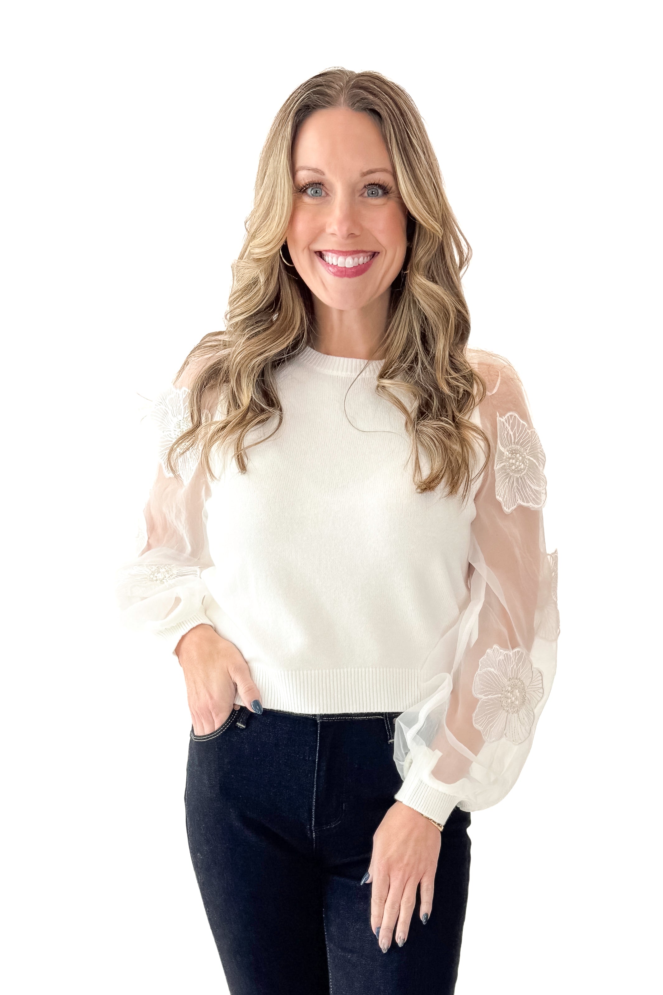 Front view of woman wearing Off White Floral Applique Sleeve Sweater with jeans against white studio background.