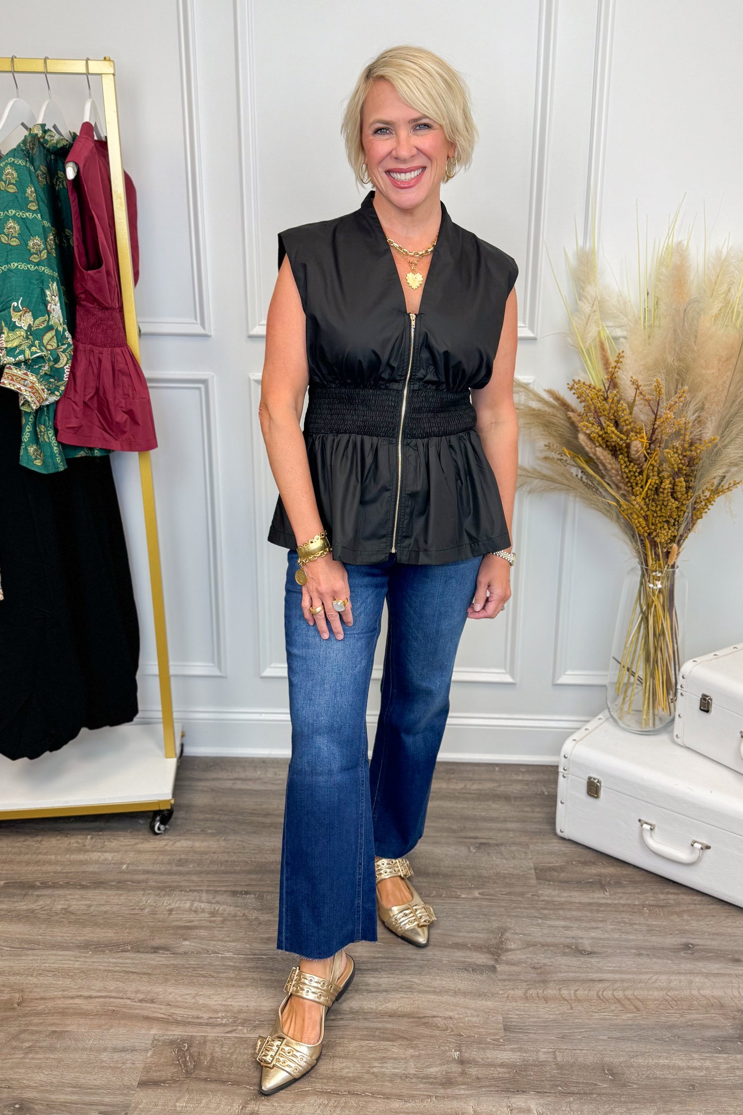 Front view of black top showing center zipper and smocked waist detailing.