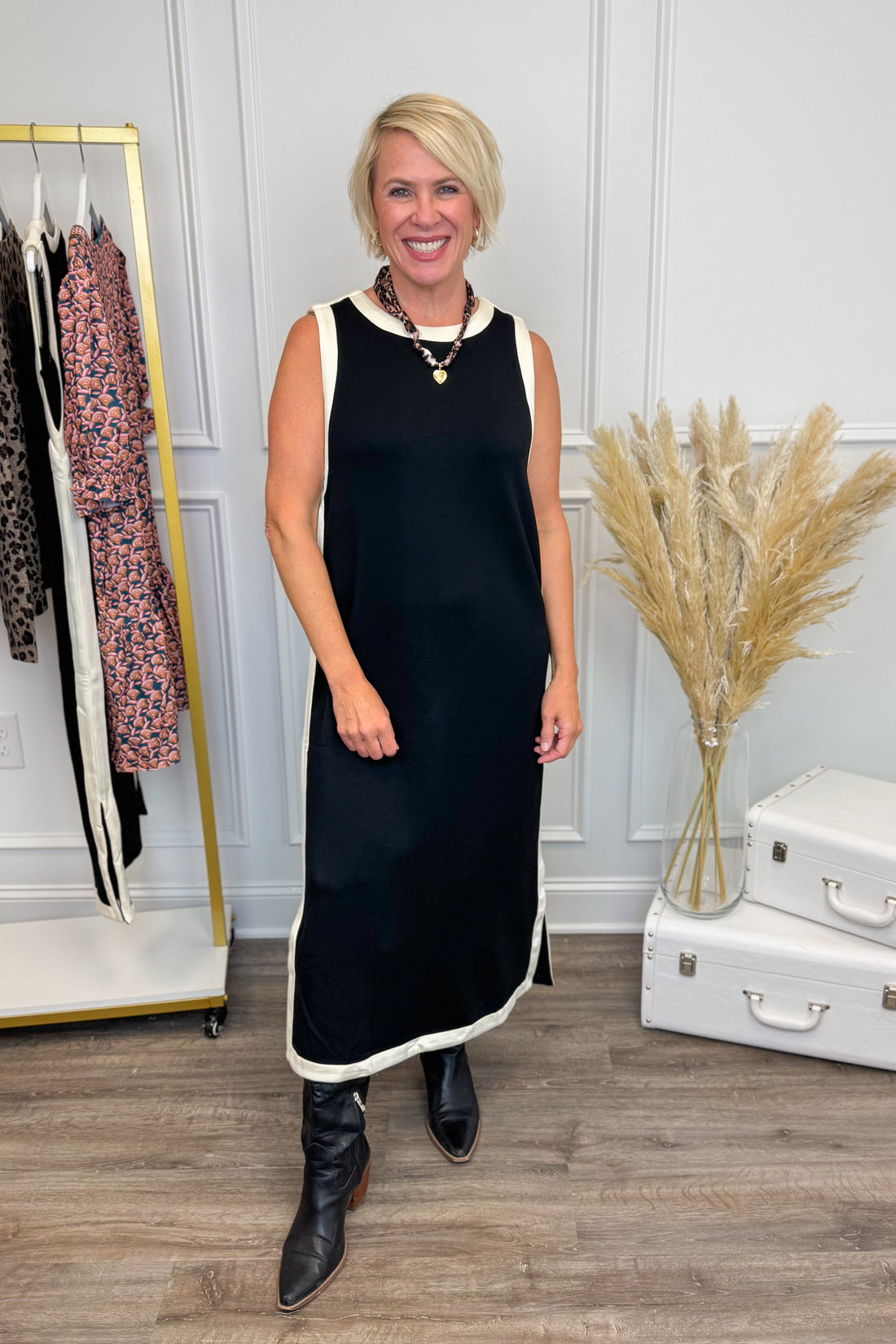 Front picture of woman wearing Black With Cream Lining Midi Dress by Entro with clothes in the background. 