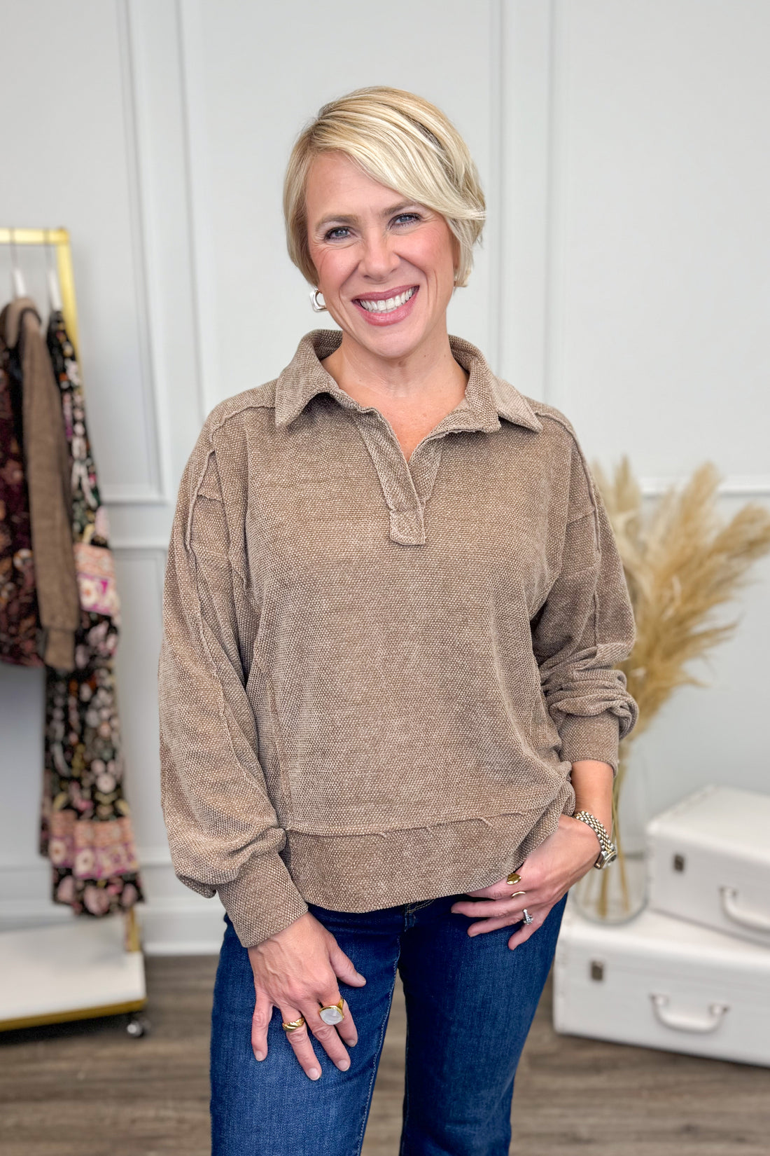 Woman wearing Mocha Chenille Collared Top and jeans with decor in the background.