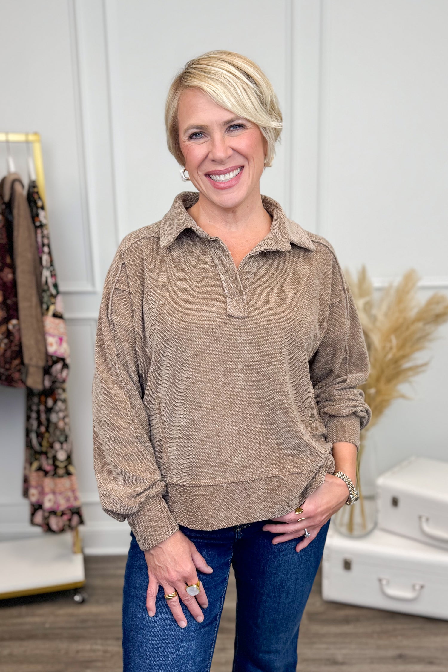 Woman wearing Mocha Chenille Collared Top and jeans with decor in the background.