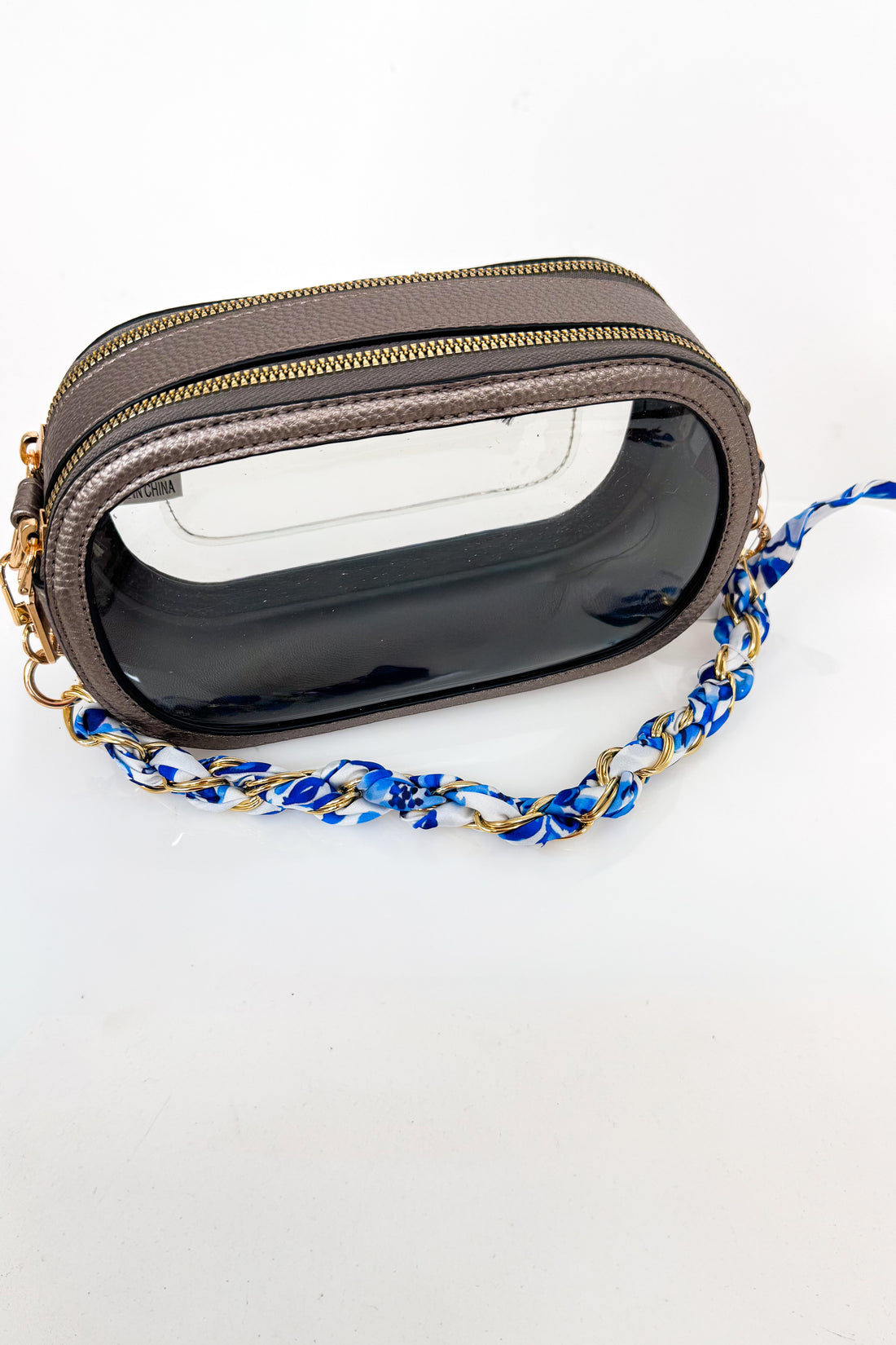 Clear pouch with gold zipper and blue chain strap on a white background
