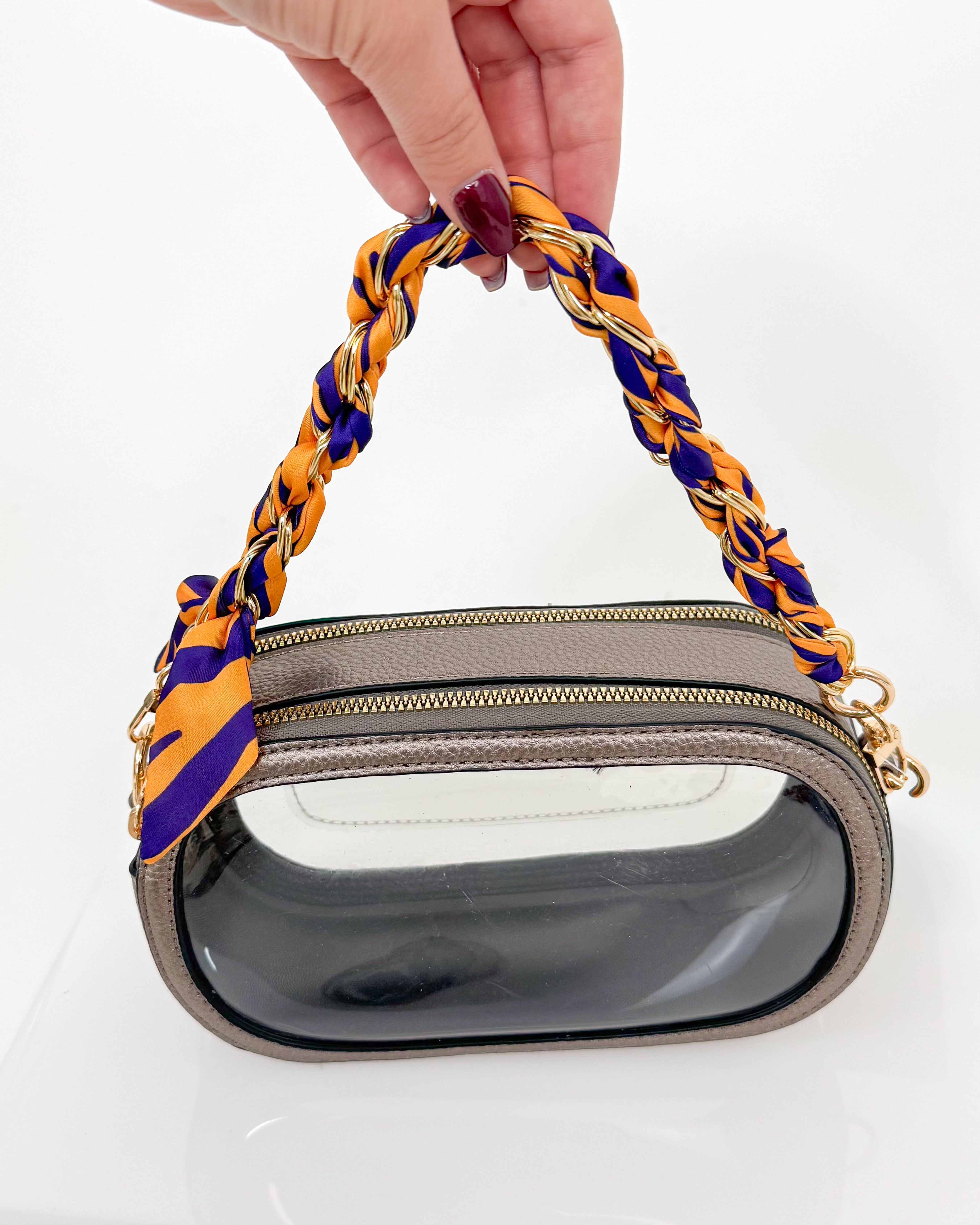 Handbag with a purple and yellow handle held by a hand on a white background