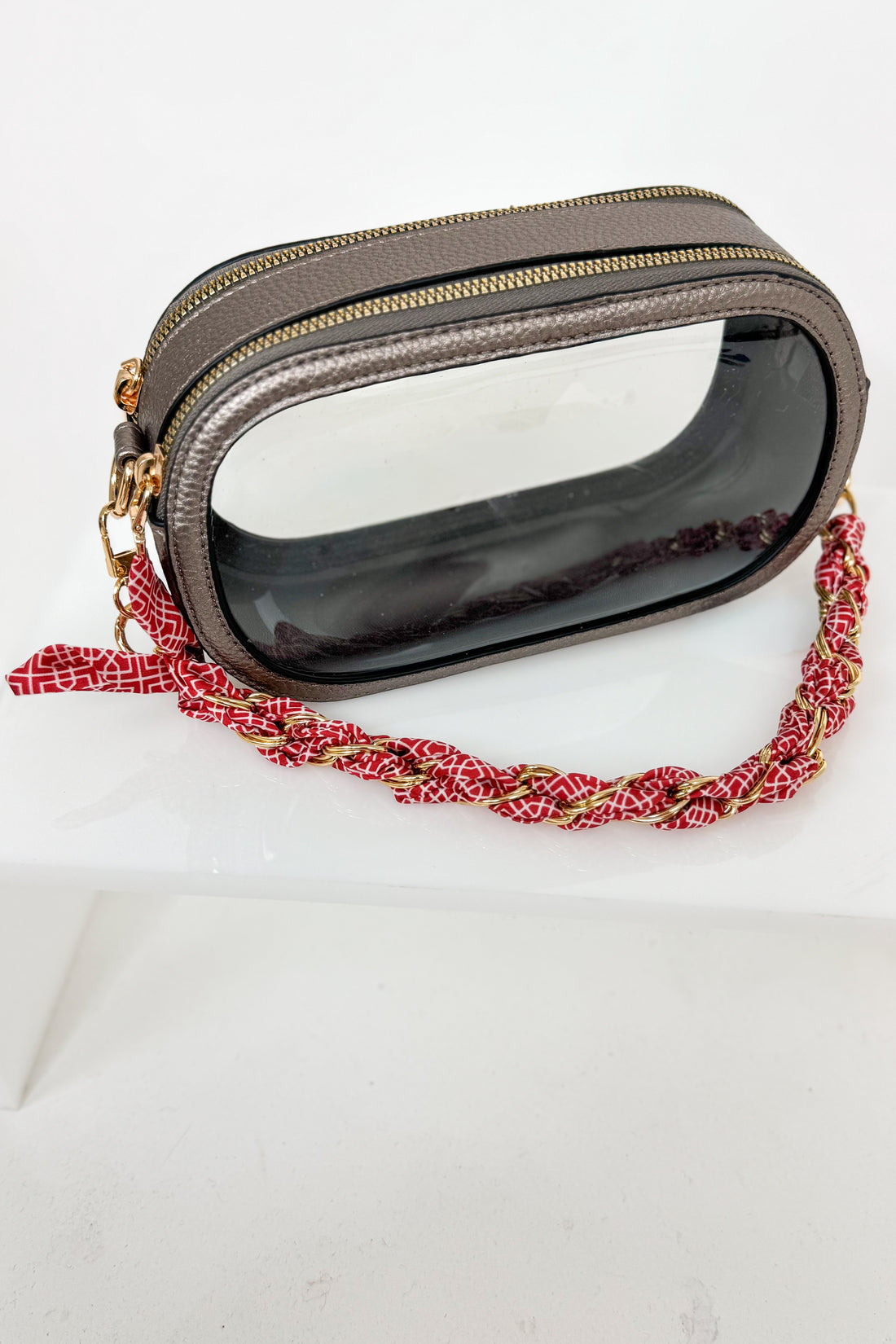 Handbag with a red and gold braided strap on a white background