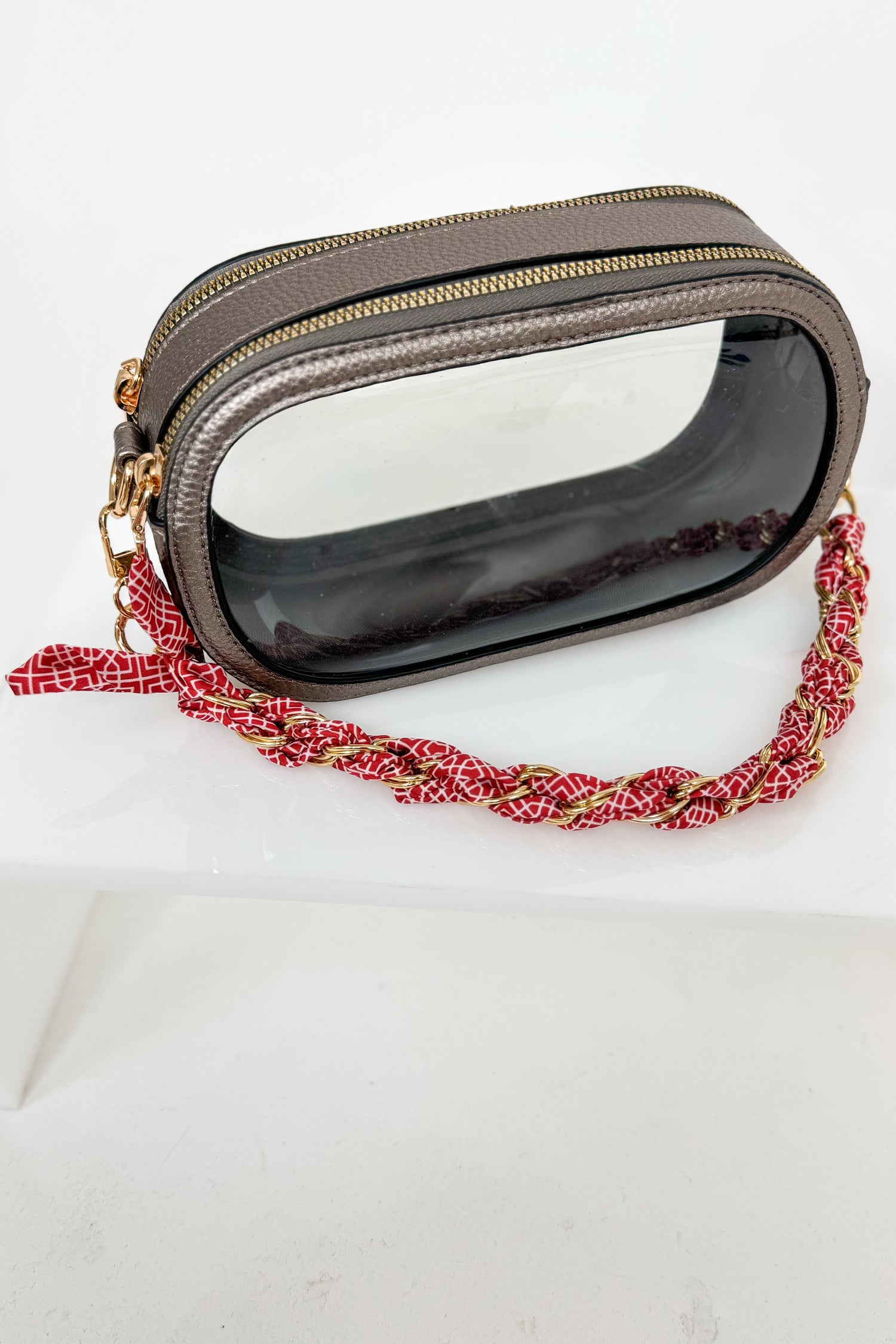 Handbag with a red and gold braided strap on a white background