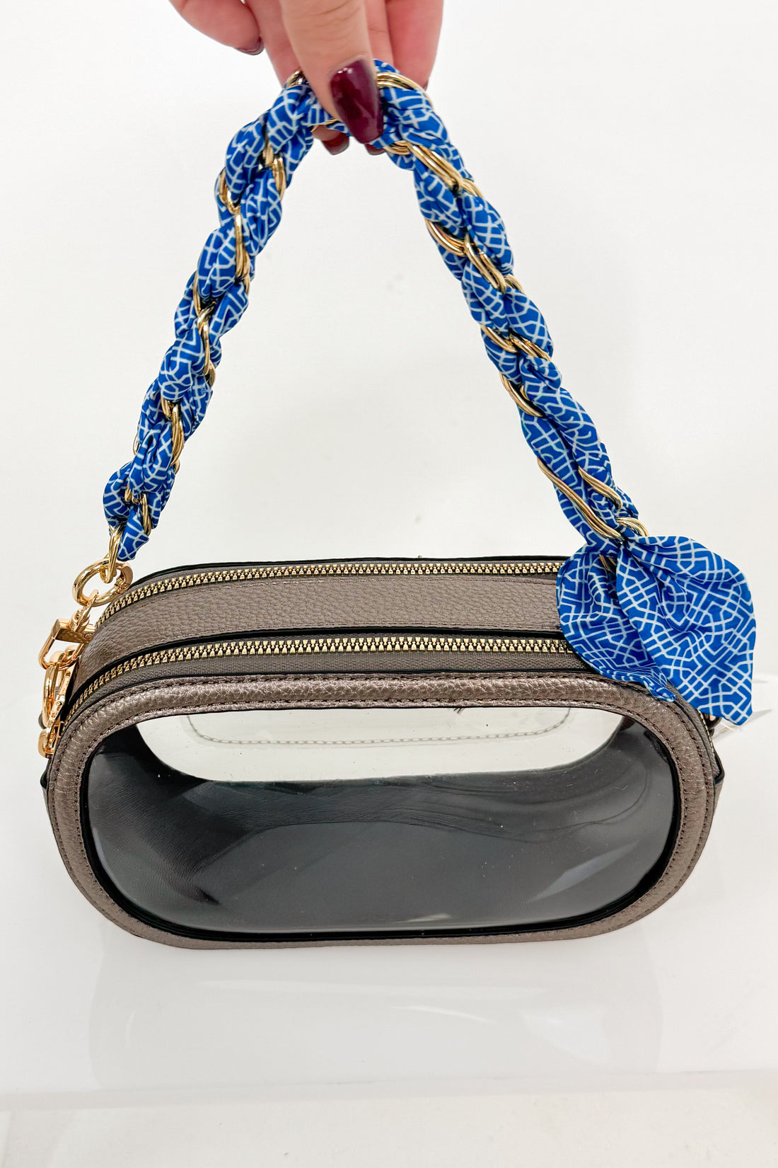 Handbag with blue braided handle held by a hand on a white background