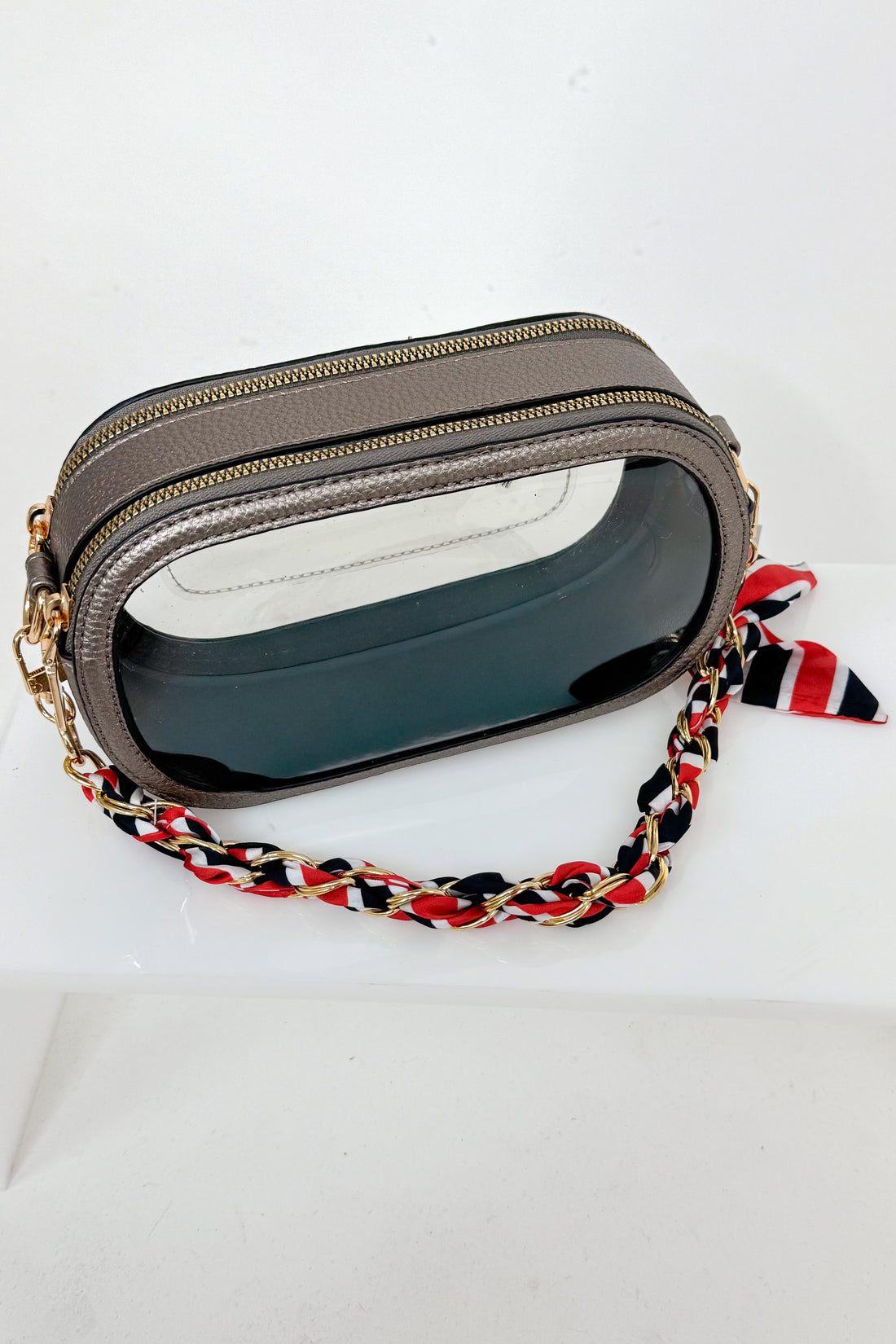 Small gray crossbody bag with a red, black, and white braided strap on a white background