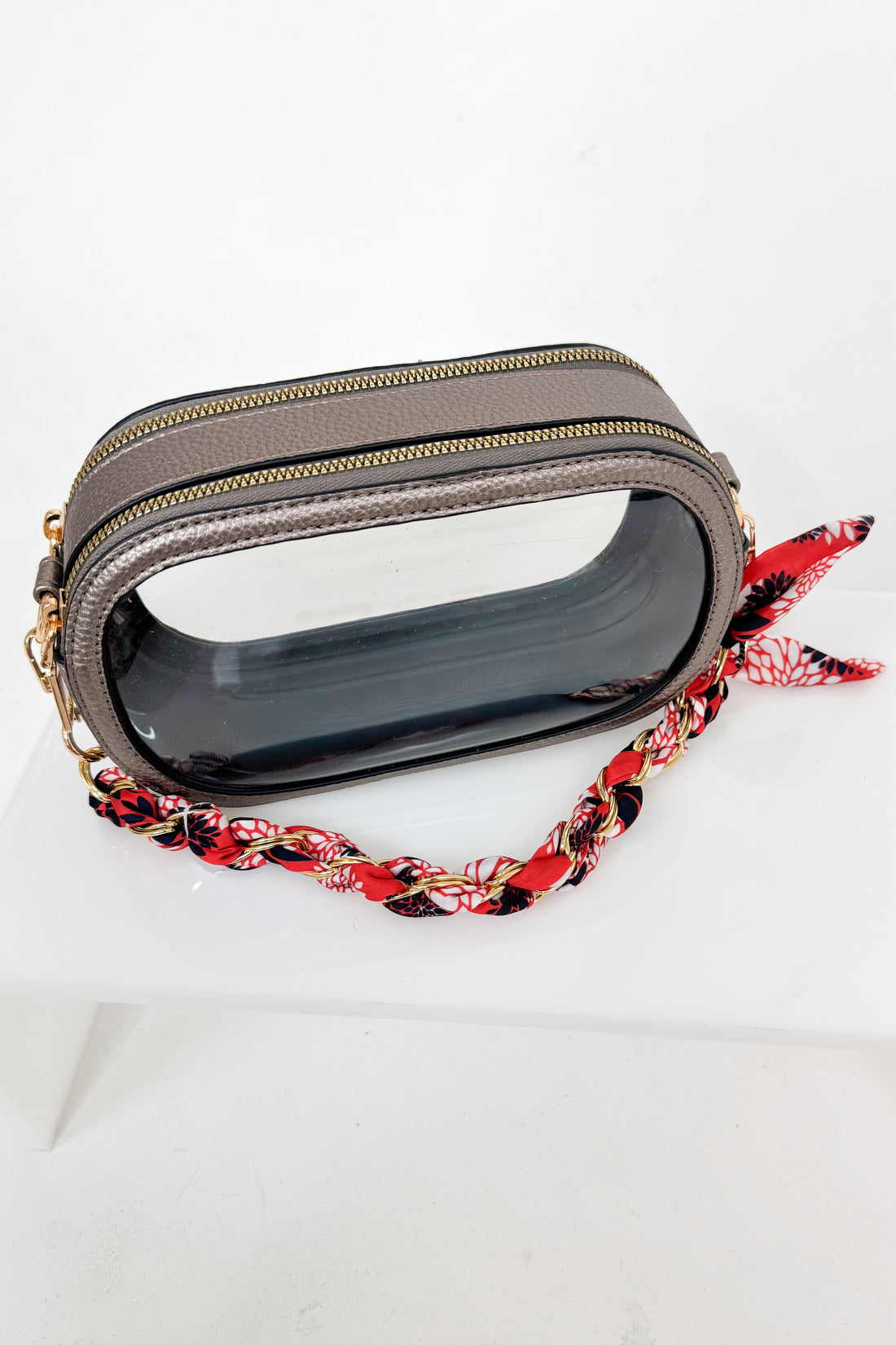 Small gray pouch with a red, black and white floral strap on a white background