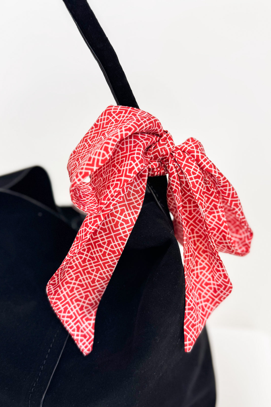 Red patterned bow tie on a black shirt against a white background