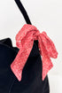 Red patterned bow tie on a black shirt against a white background