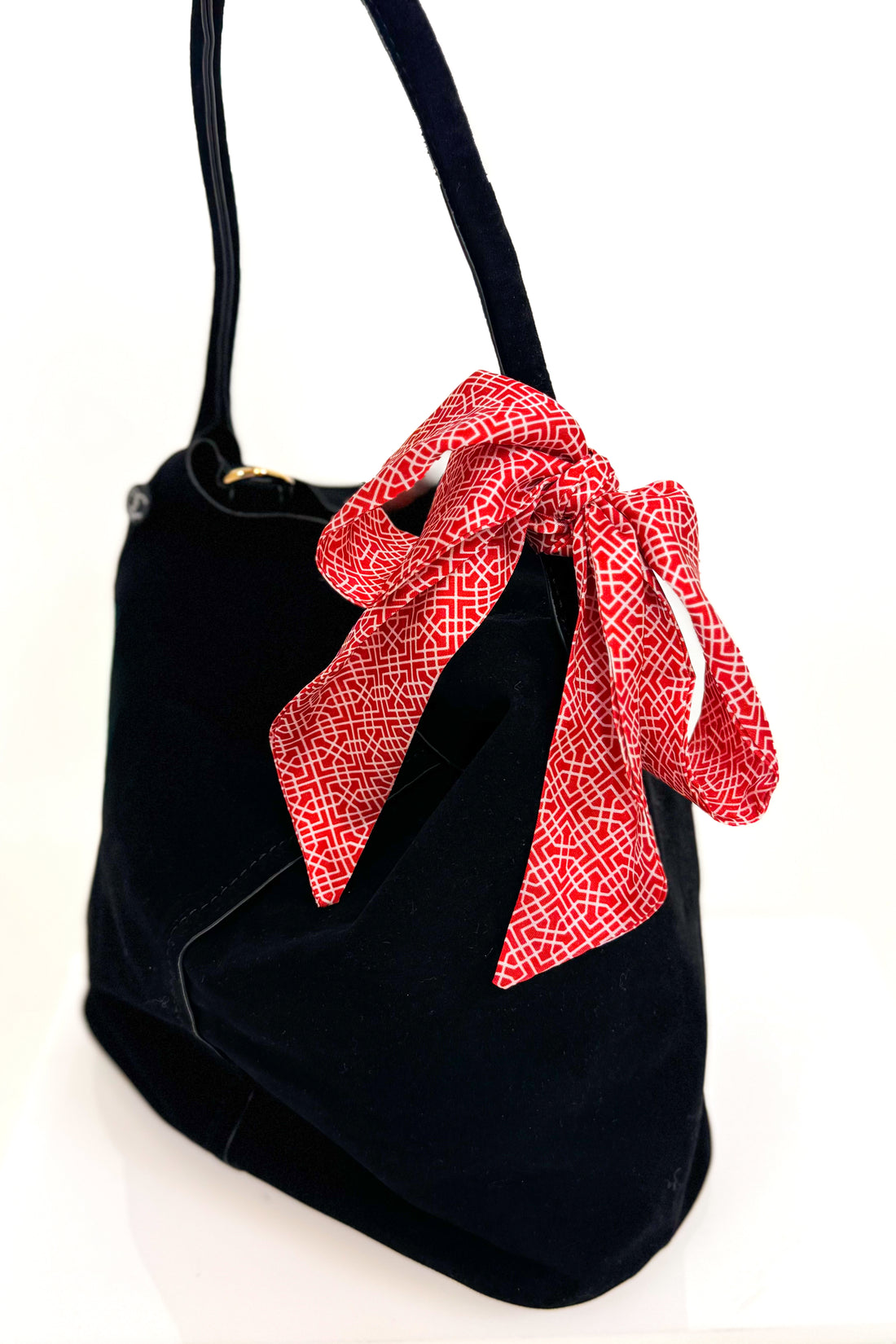 Black handbag with a red bow on a white background