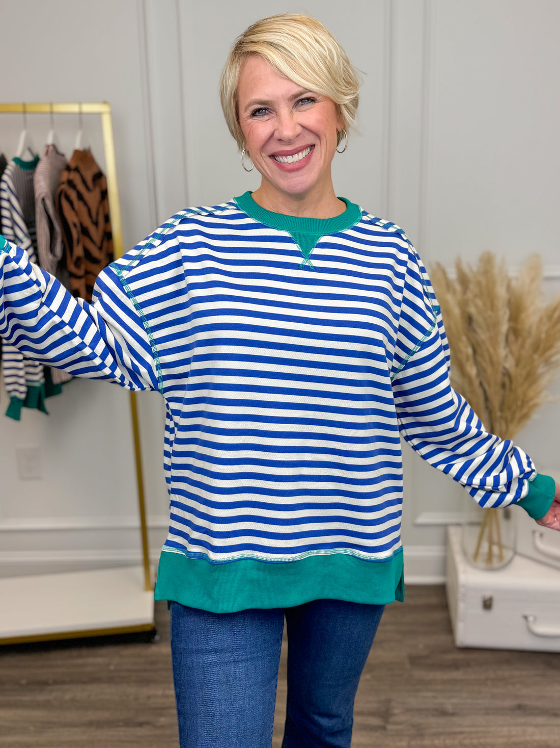 Woman wearing a blue and white striped sweater with green trim in a room setting.