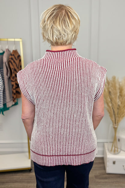 Person wearing a red and white striped vest in a room with decor elements.