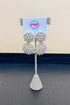 Pearl earrings on a decorative stand with a branded card against a neutral background