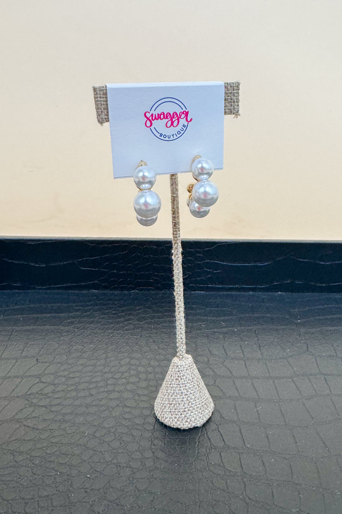 Pair of pearl earrings on a stand with a &