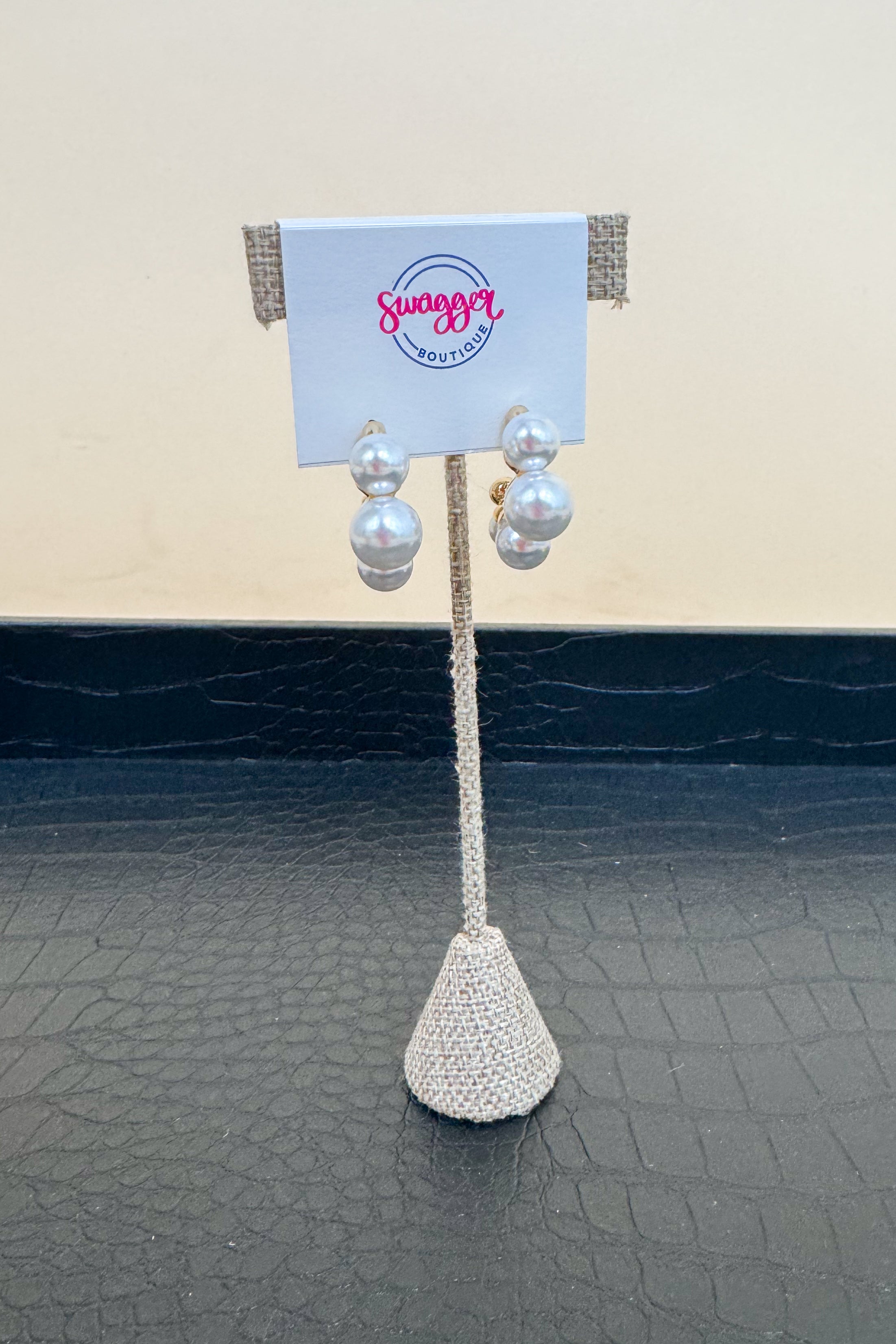 Pair of pearl earrings on a stand with a &