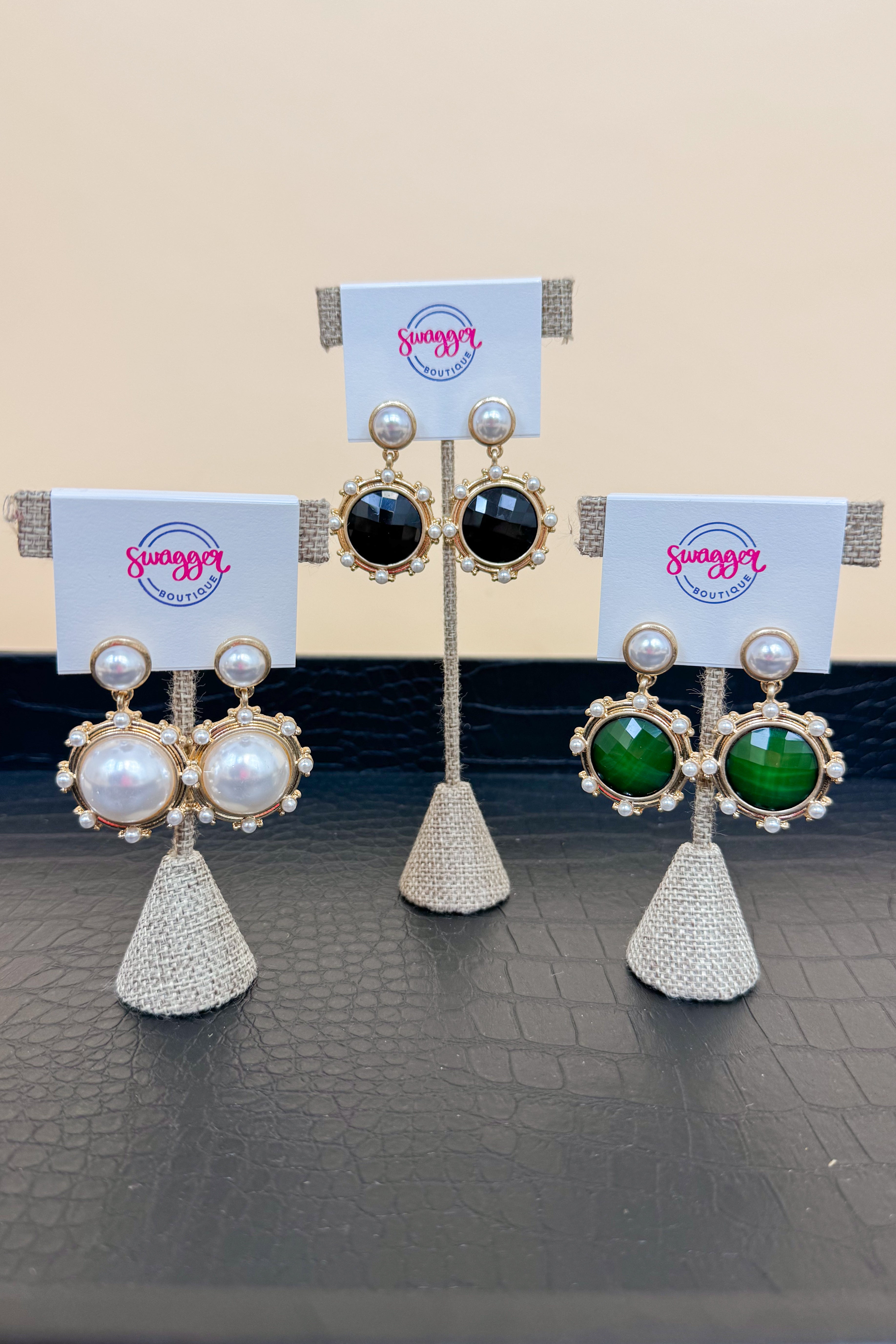 Three pairs of earrings on a stand with &