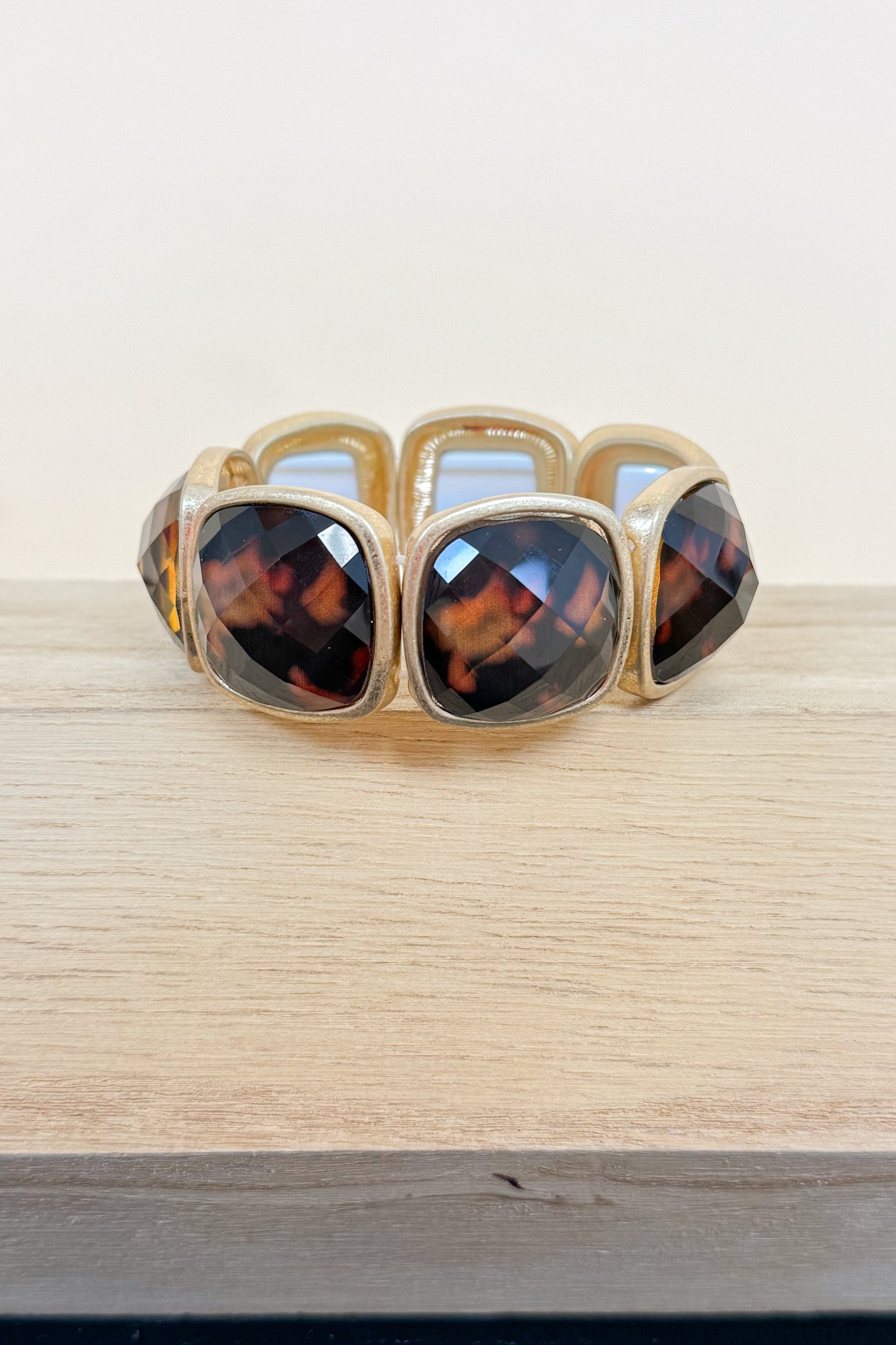 Gold bracelet with tortoiseshell stones on a wooden surface