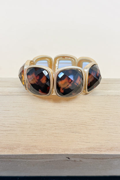 Gold bracelet with tortoiseshell stones on a wooden surface
