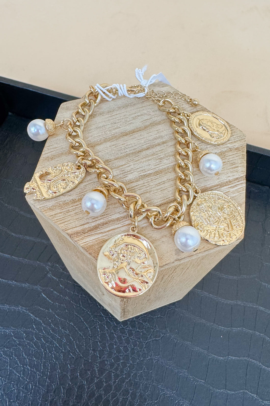 Gold bracelet with charms on a wooden block