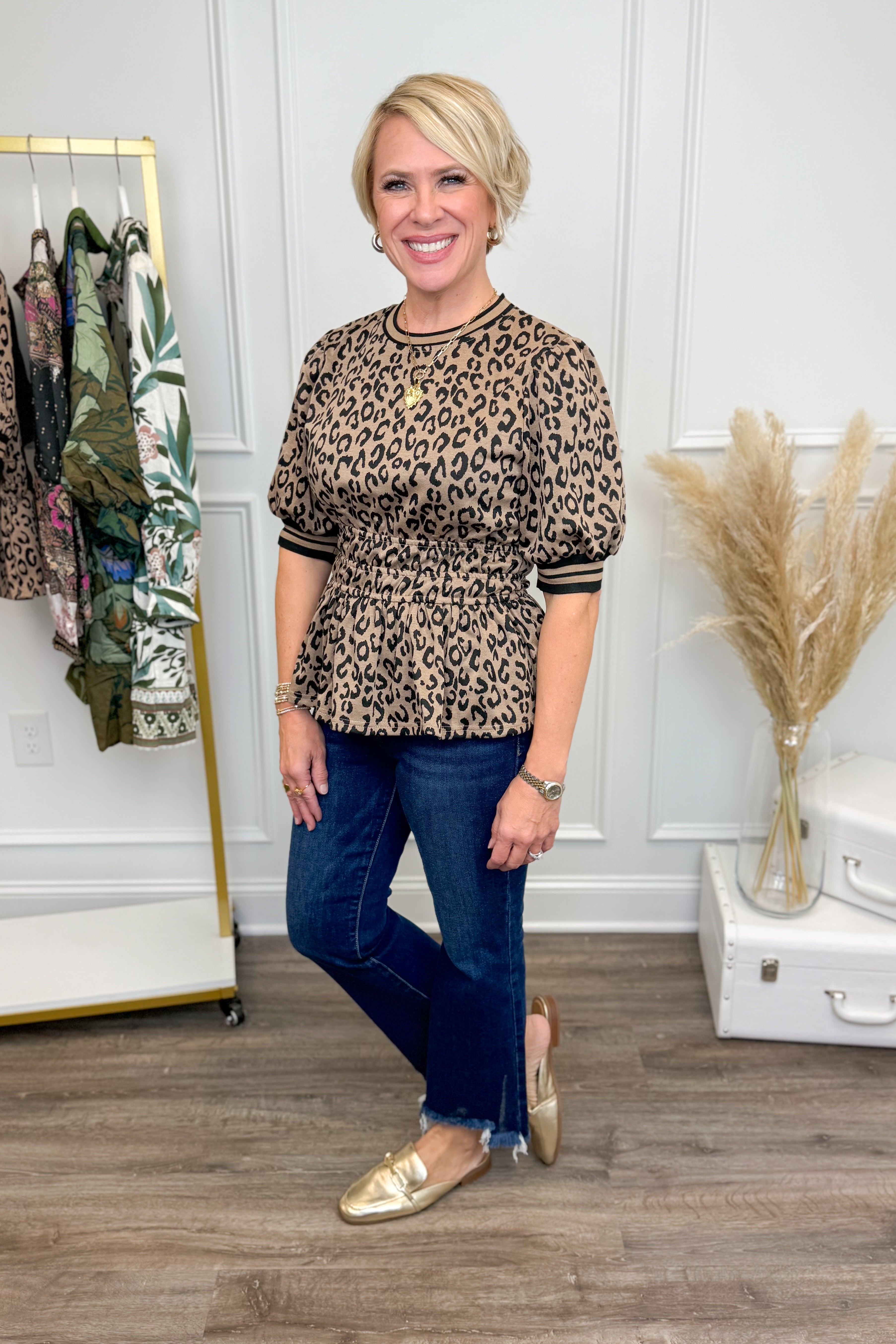Woman wearing a leopard print top and blue jeans in an indoor setting.