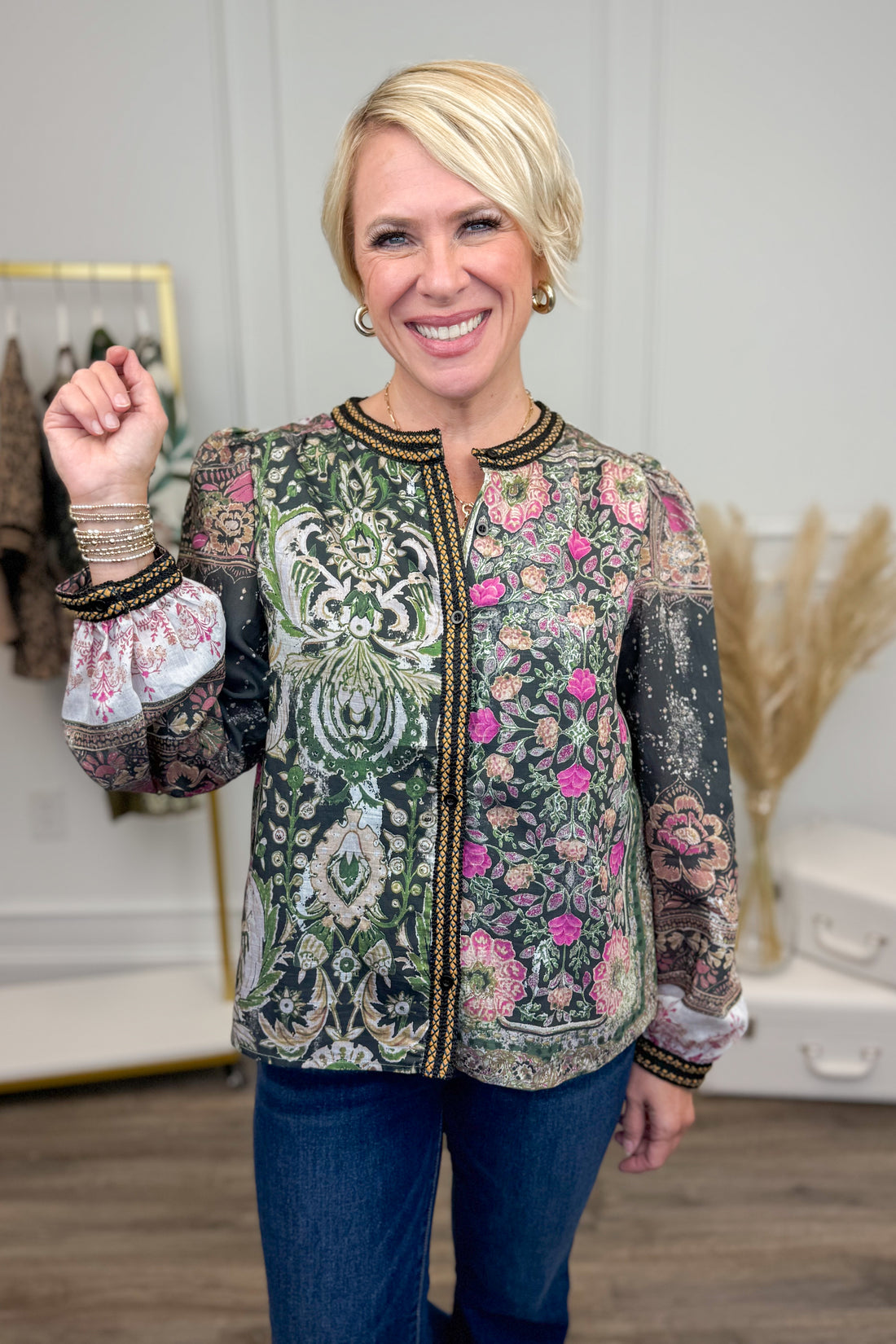 Woman wearing a patterned shirt with floral and paisley designs indoors.