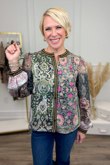 Woman wearing a patterned shirt with floral and paisley designs indoors.