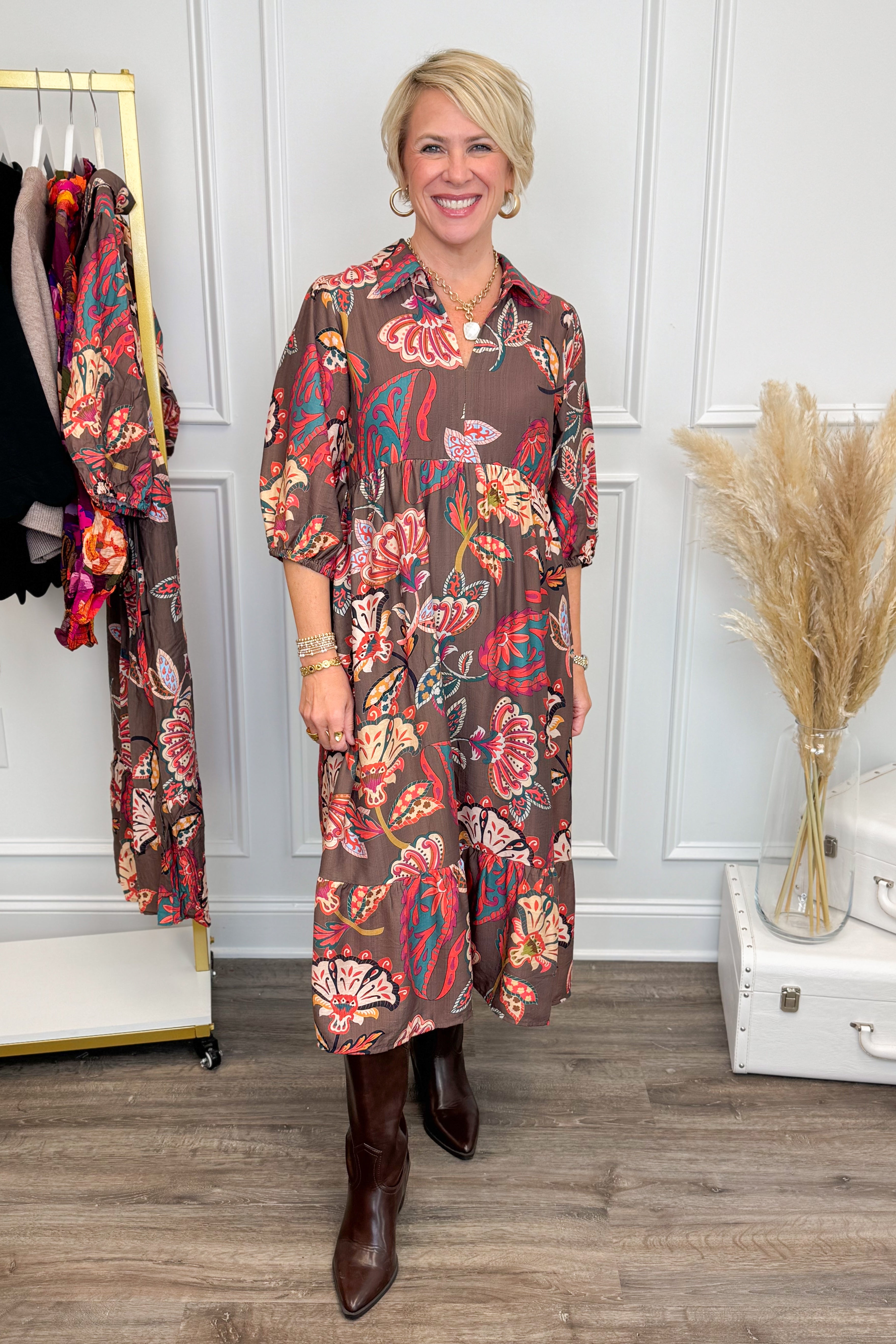 Woman wearing a floral dress in a room with decor elements.