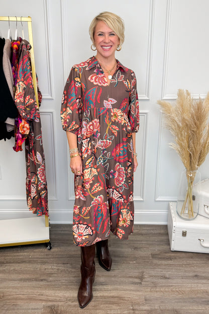 Woman wearing a floral dress in a room with decor elements.