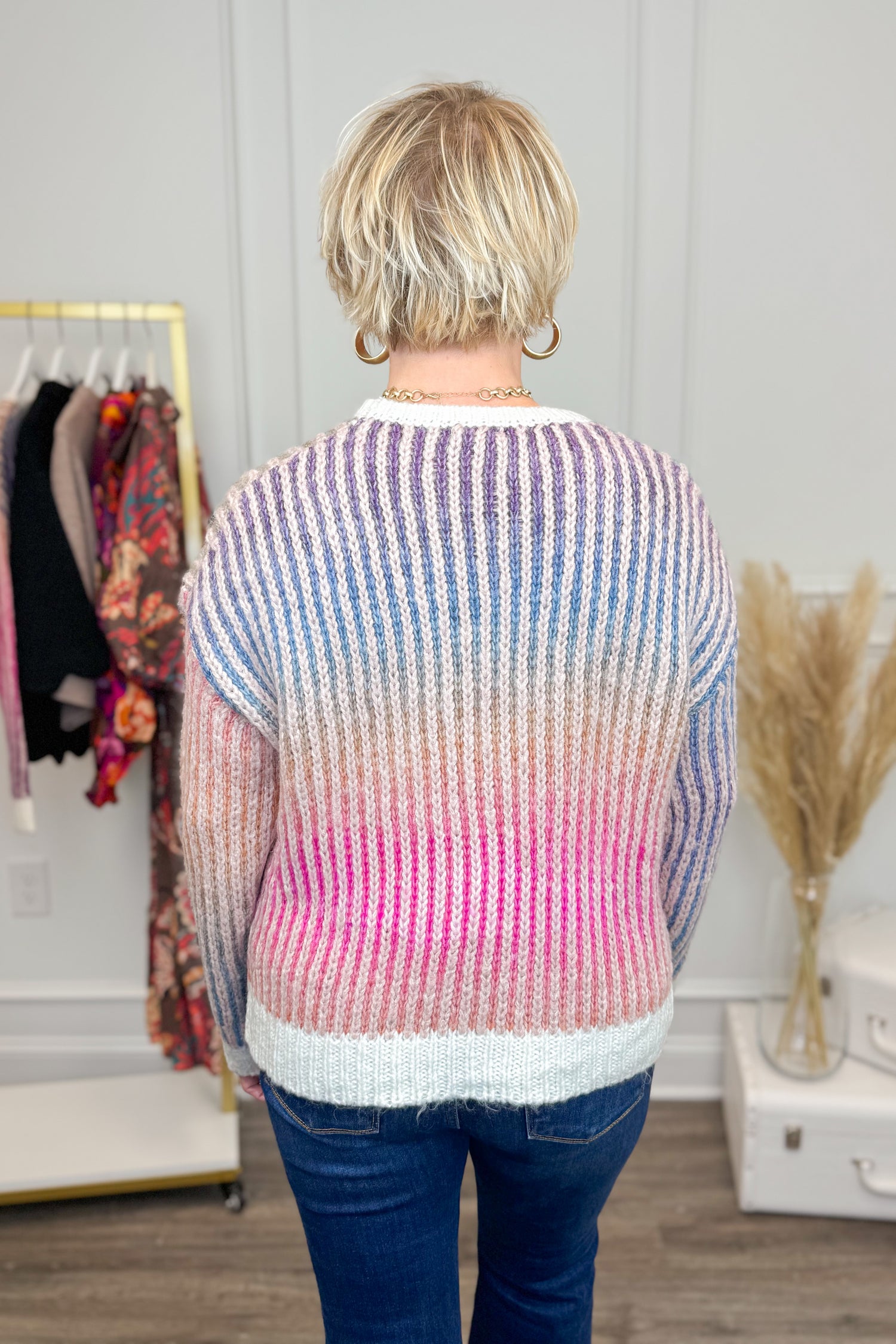 Person wearing a colorful striped sweater in a clothing store.
