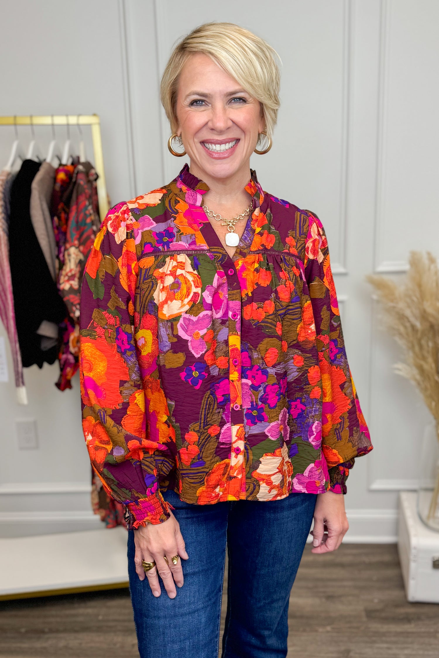 Woman wearing a colorful floral shirt in a clothing store setting