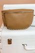 Tan leather bag with studs on a white suitcase against a beige background