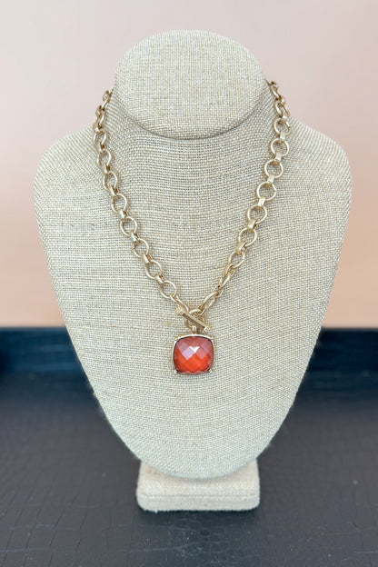 Necklace with a brown pendant on a gray bust against a beige background