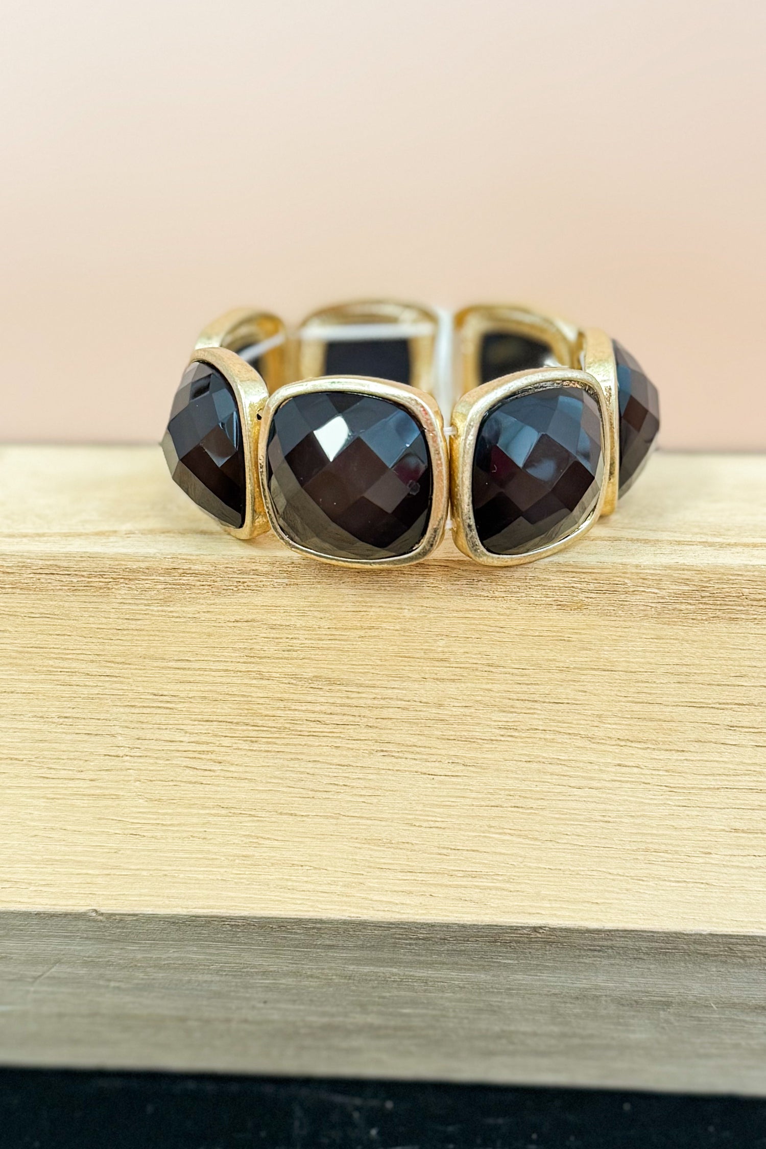Gold bracelet with black stones on a wooden surface