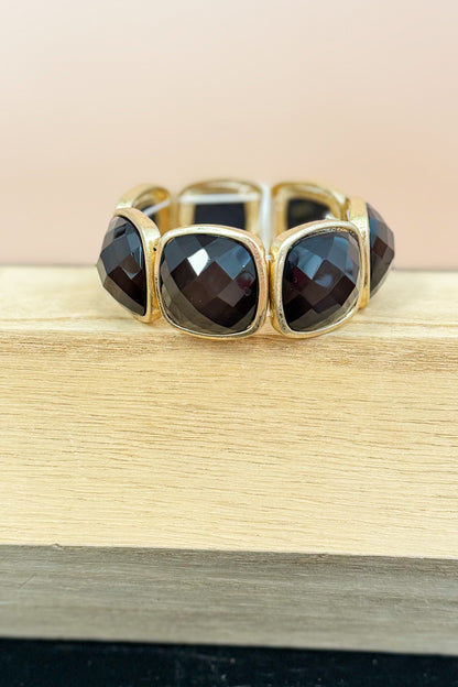 Gold bracelet with black stones on a wooden surface