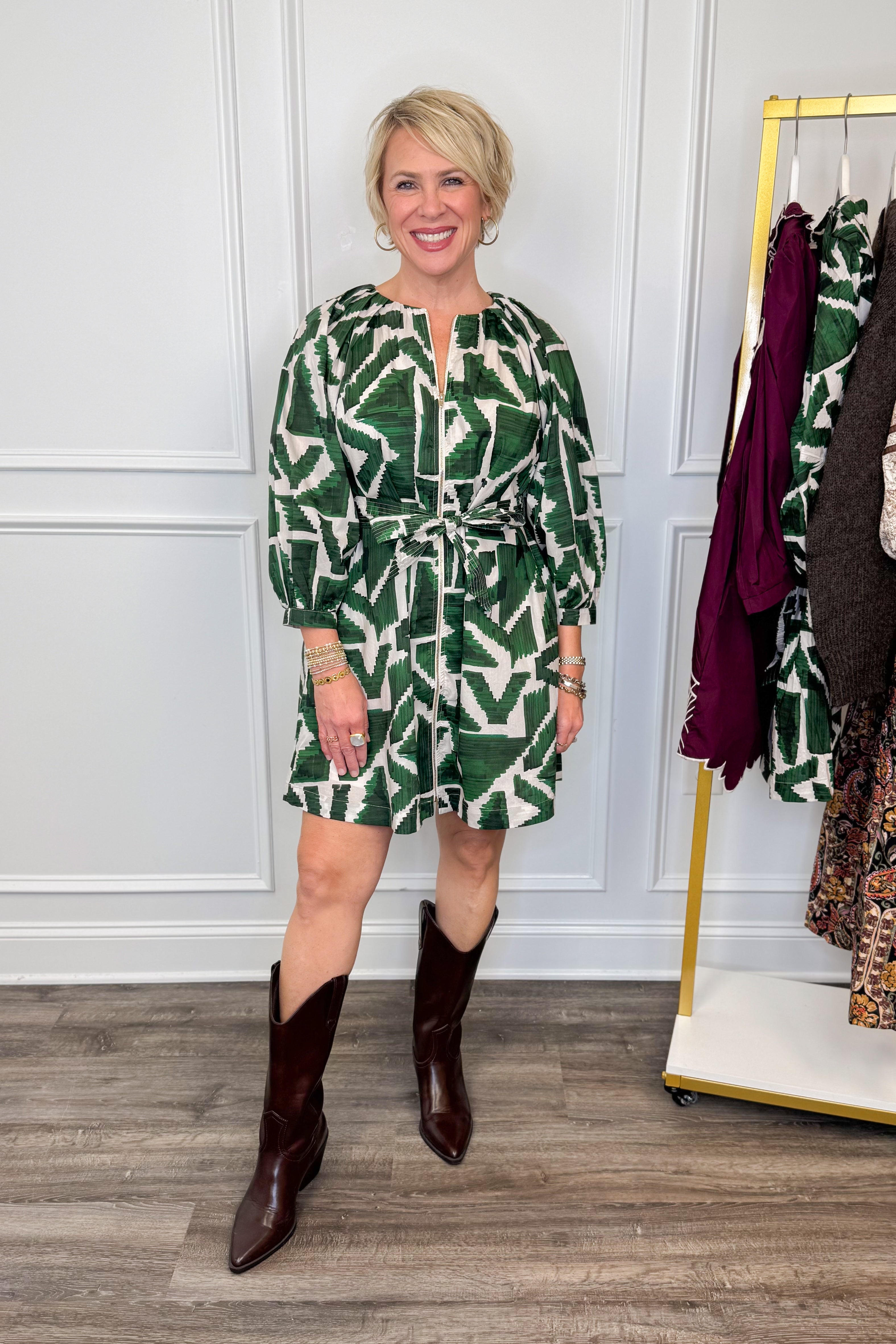 woman wearing green abstract printed tie waist dress with brown boots