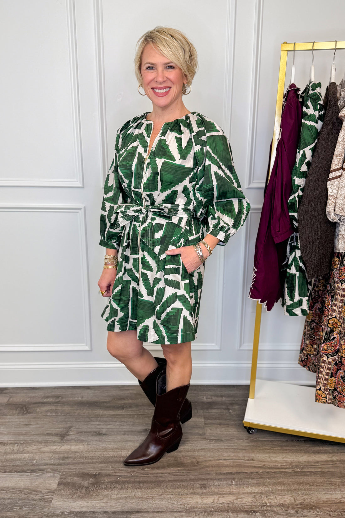 woman wearing green abstract printed tie waist dress with brown boots