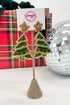 Christmas tree earrings on a stand with a colorful background
