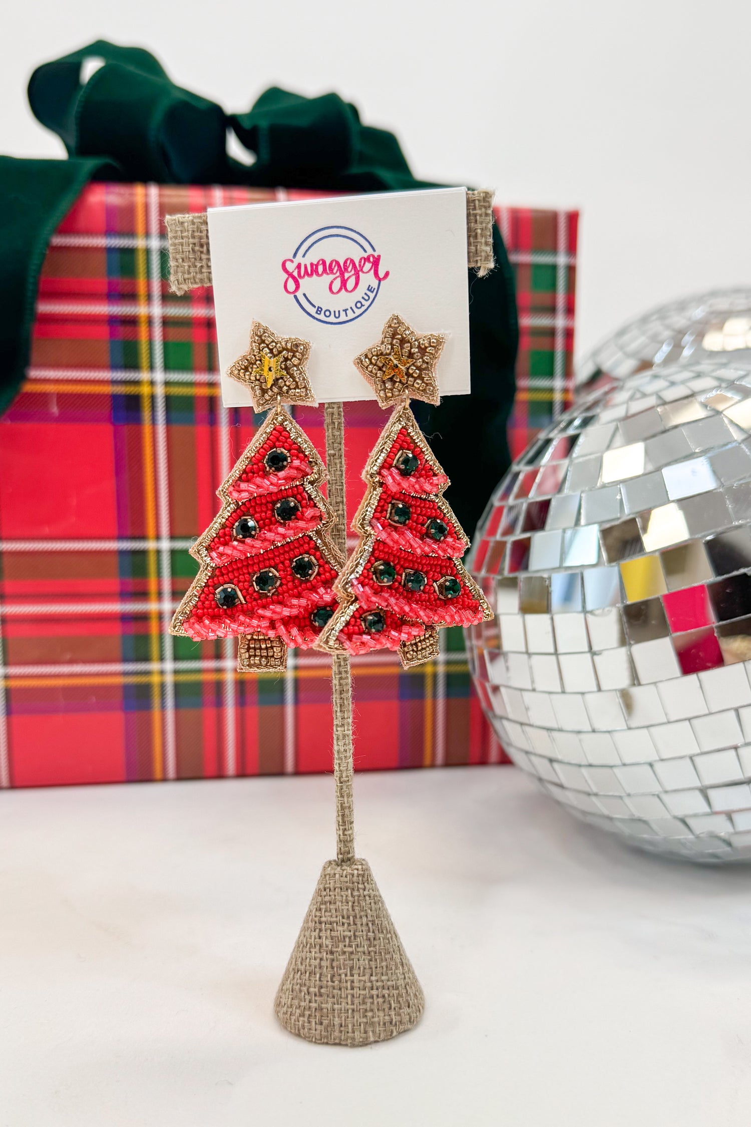 Red Christmas tree earrings on a stand with a &