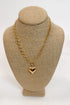 Gold chain necklace with a heart pendant on a beige bust
