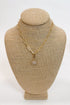 Gold necklace with a star-shaped pendant on a beige bust against a white background