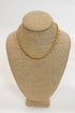 Gold chain necklace on a beige mannequin bust against a white background