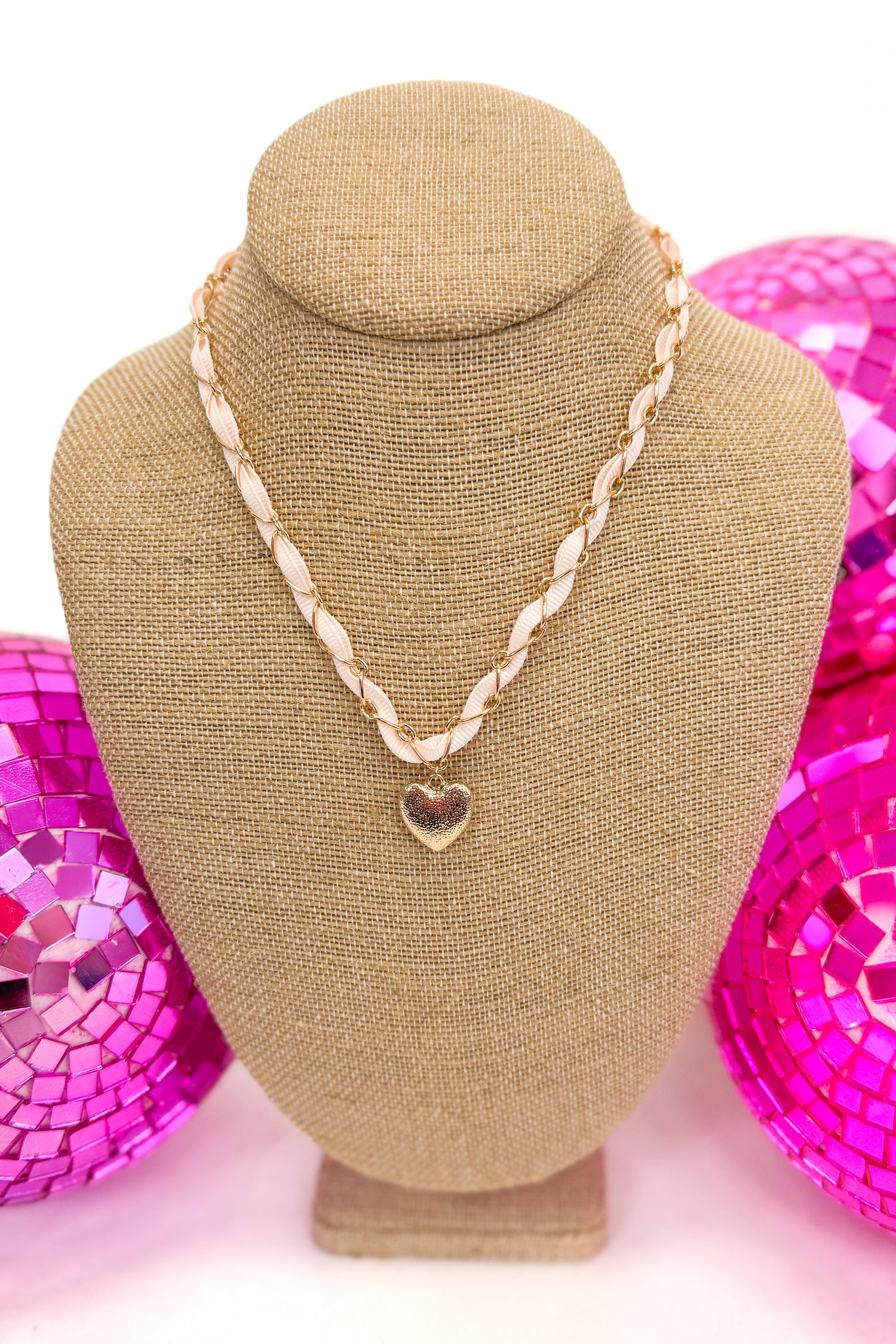 necklace with light pink ribbon and chain surrounding ribbon with a small heart pendant