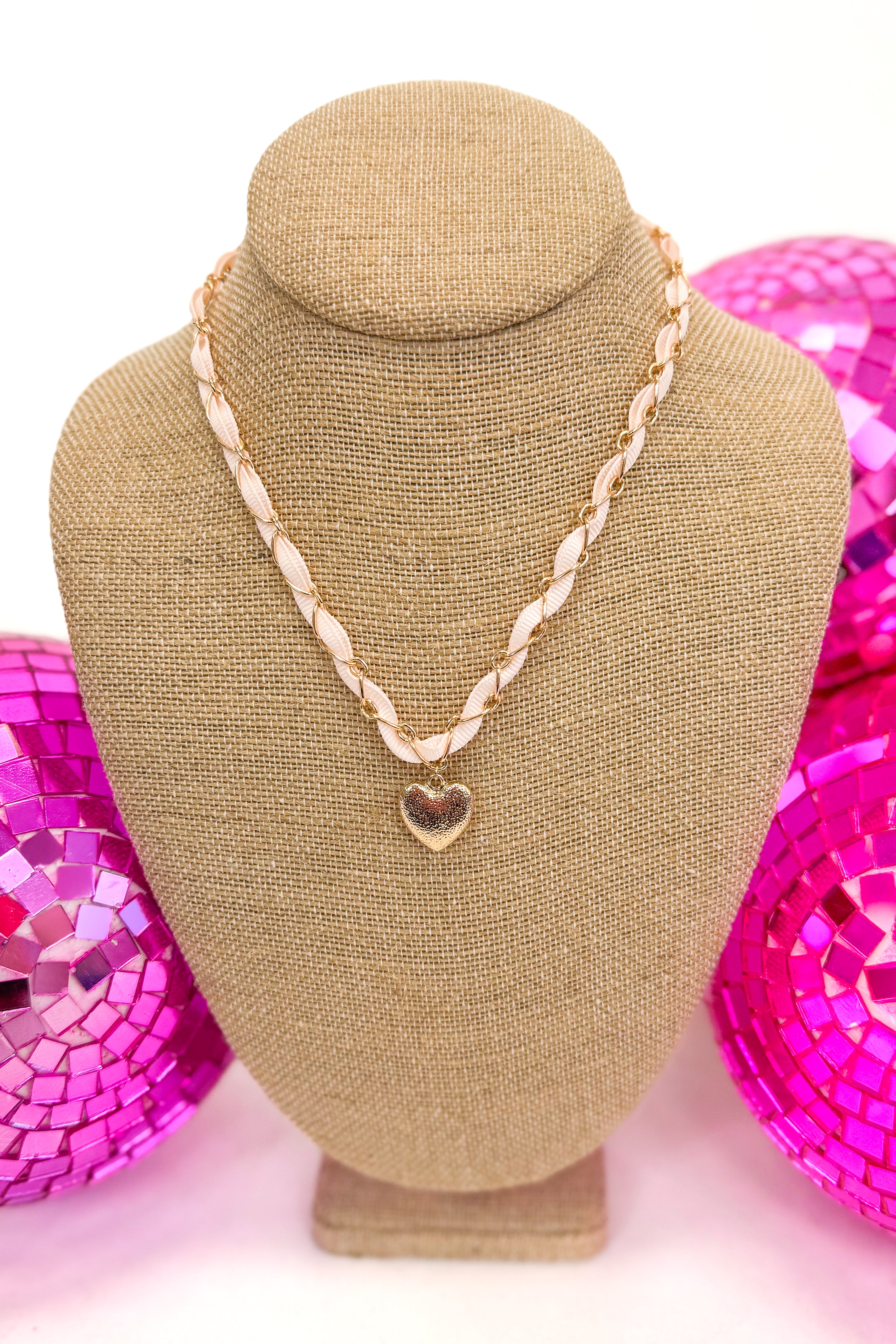 necklace with light pink ribbon and chain surrounding ribbon with a small heart pendant