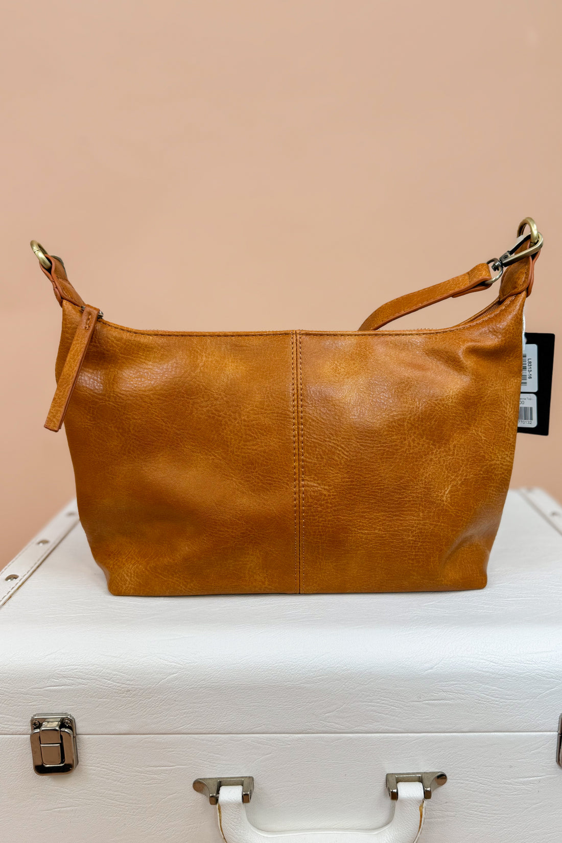 Brown leather handbag on a white suitcase with a beige background