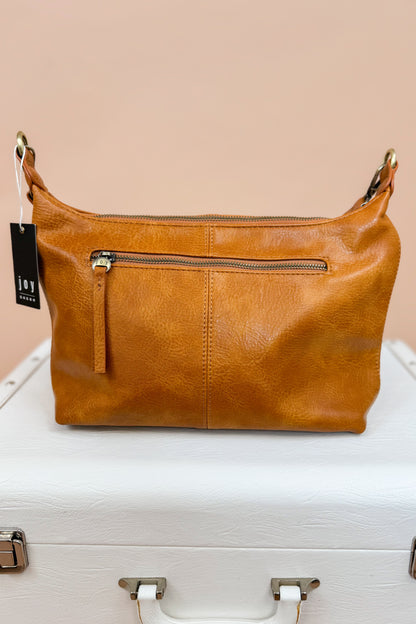 Brown leather handbag with a visible tag on a white surface