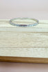 Silver bracelet on a wooden surface with a neutral background