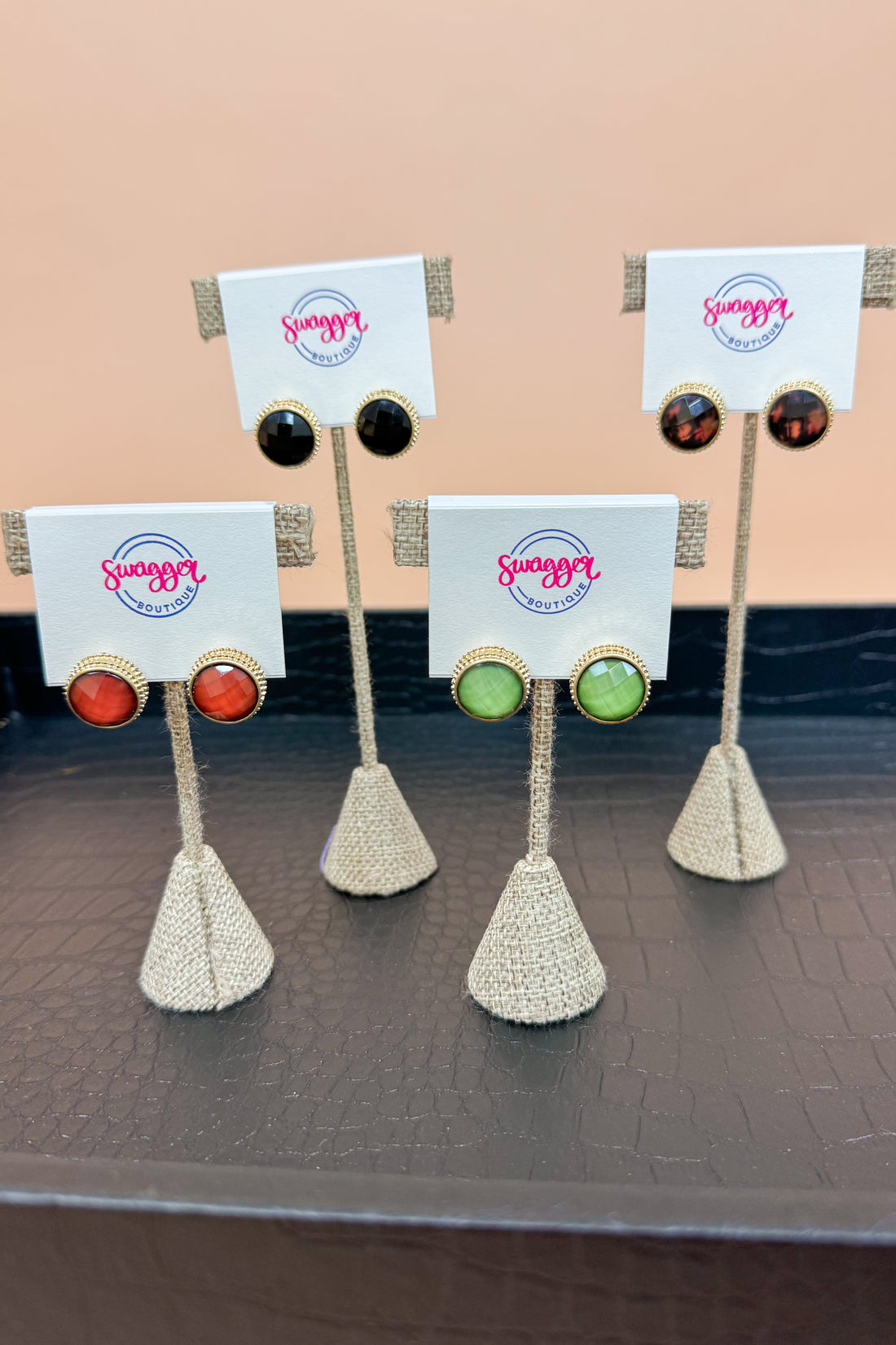 Set of earrings on stands with cards displaying a brand name against a beige background