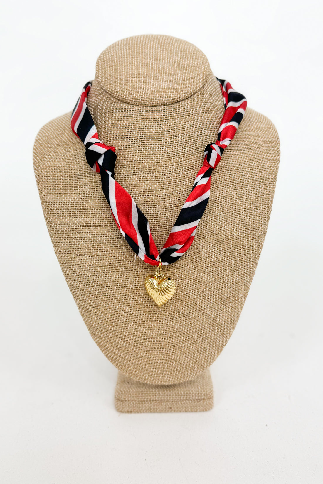 Necklace with a heart-shaped pendant on a beige bust against a white background