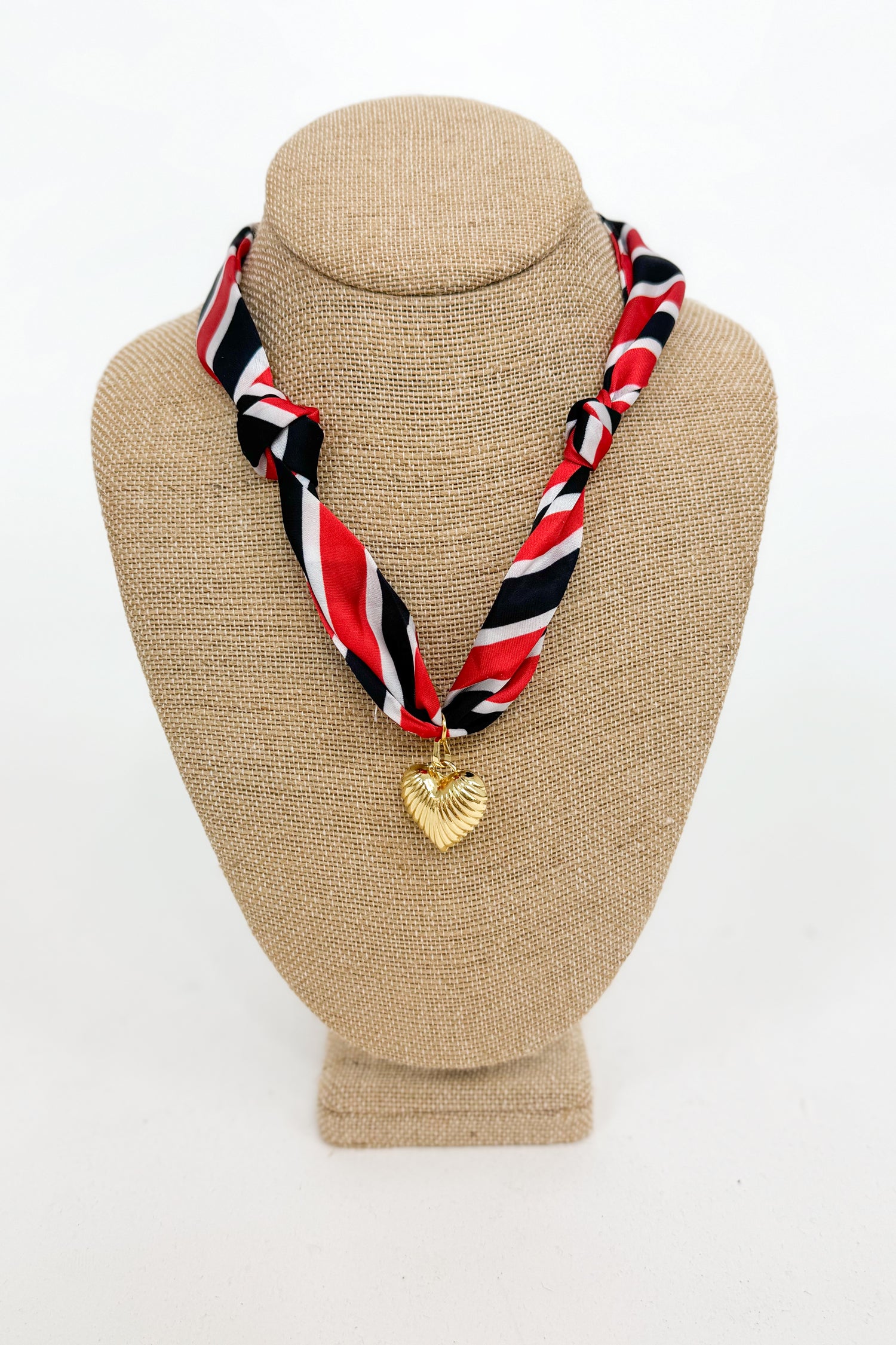 Necklace with a heart-shaped pendant on a beige bust against a white background